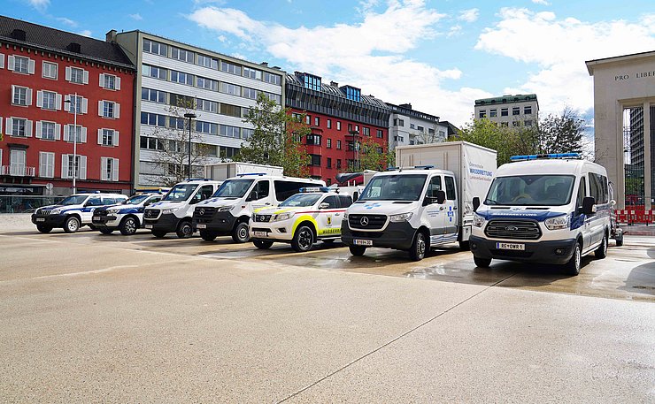 Wasserrettungsfahrzeuge (SUV, Klein-LKW, Manschaftstransporter) auf Landhaus parkend 